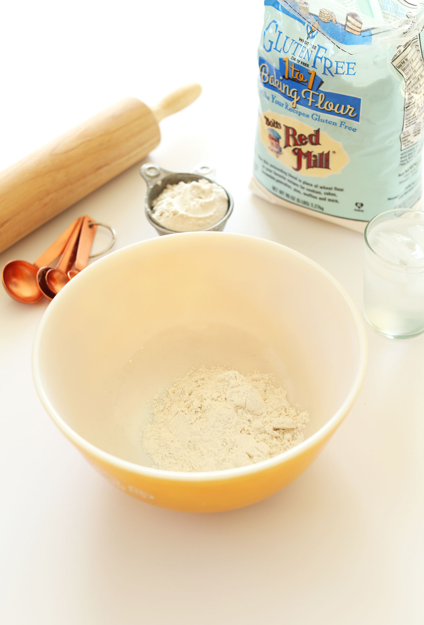 Bowl and measuring cup of Bob's Red Mill Gluten-Free Baking Flour next to a rolling pin and measuring spoons