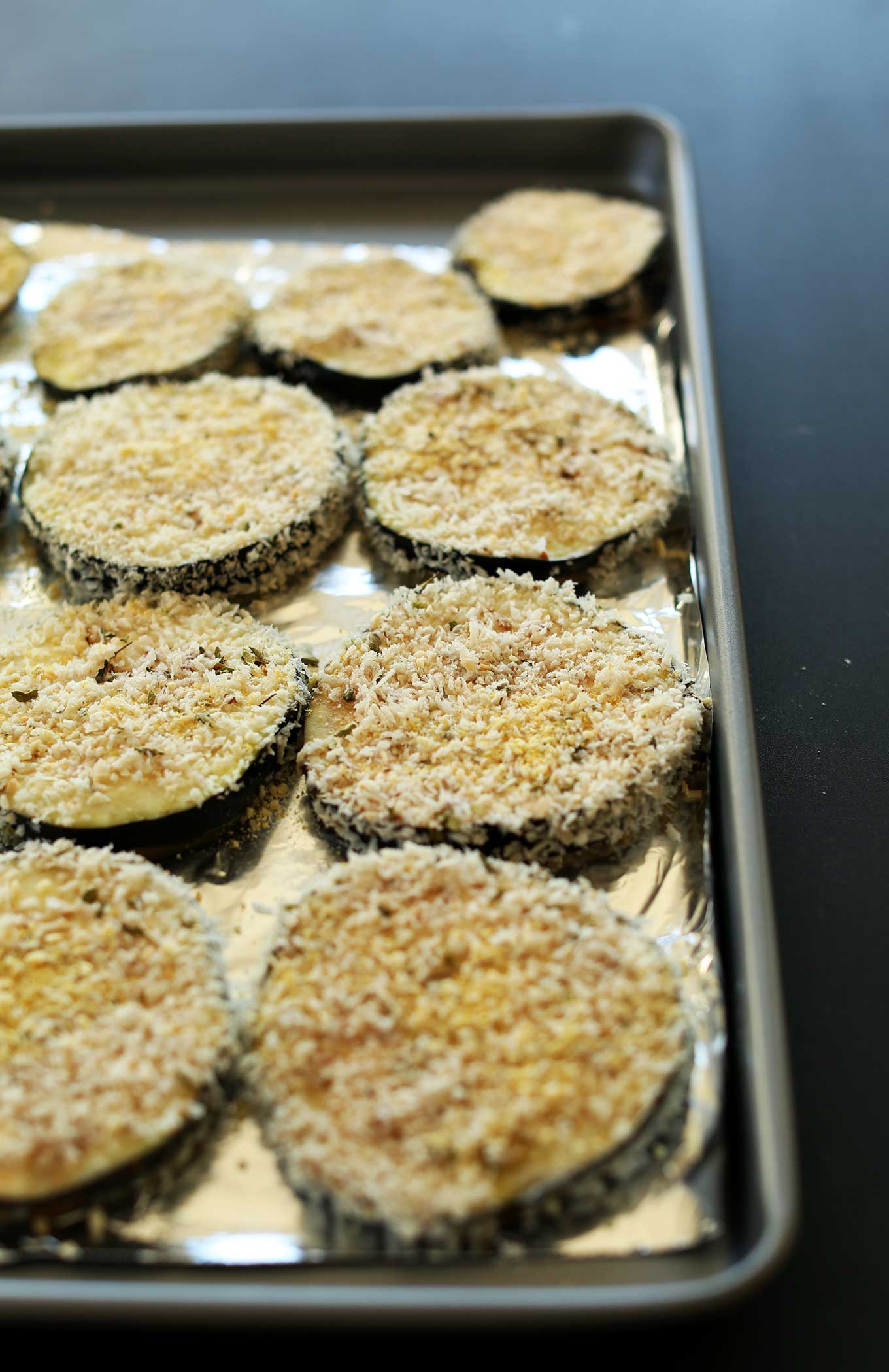 Breaded eggplant slices on a baking sheet for making our vegan eggplant parmesan recipe