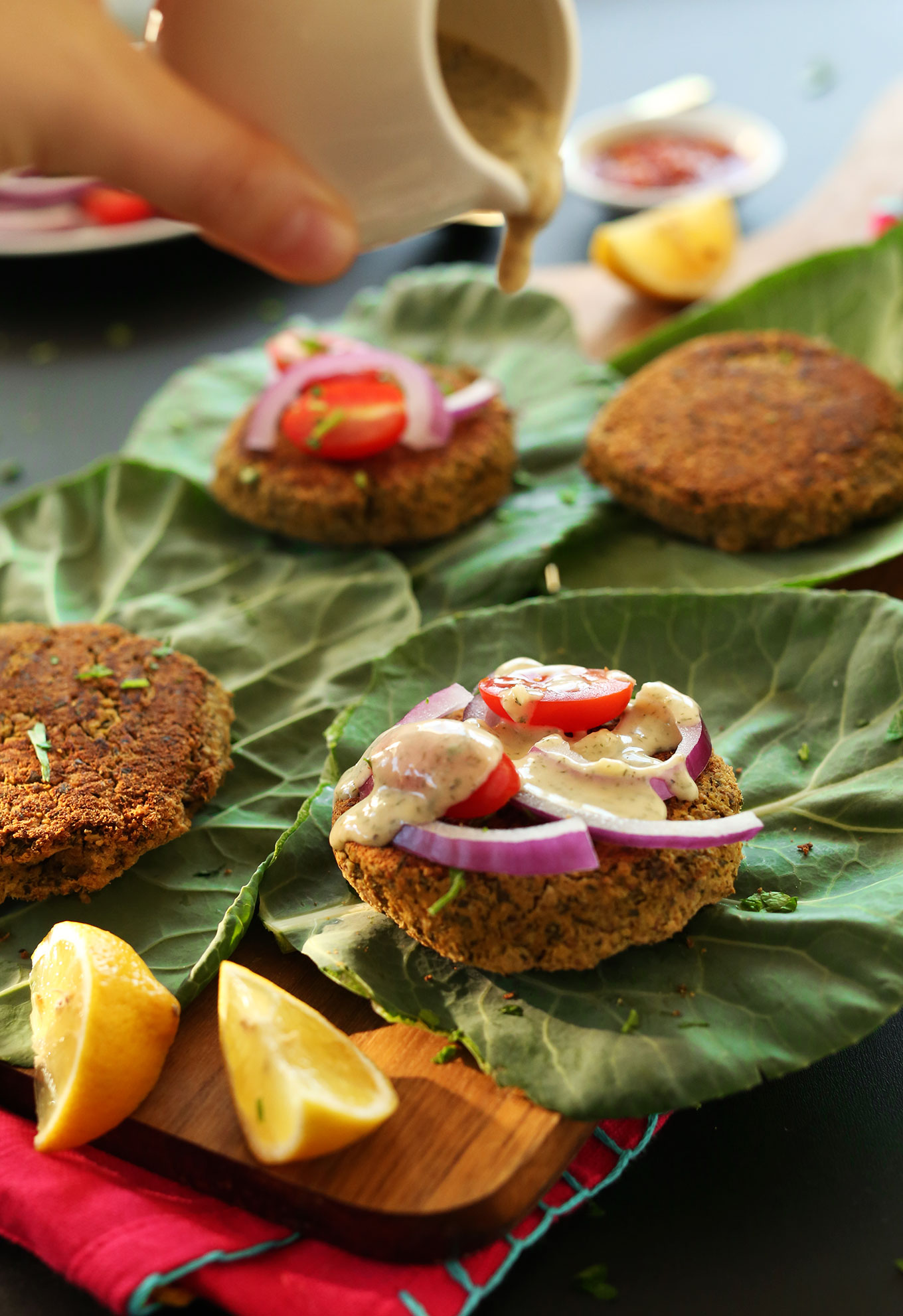 Pouring sauce over healthy baked falafel burgers