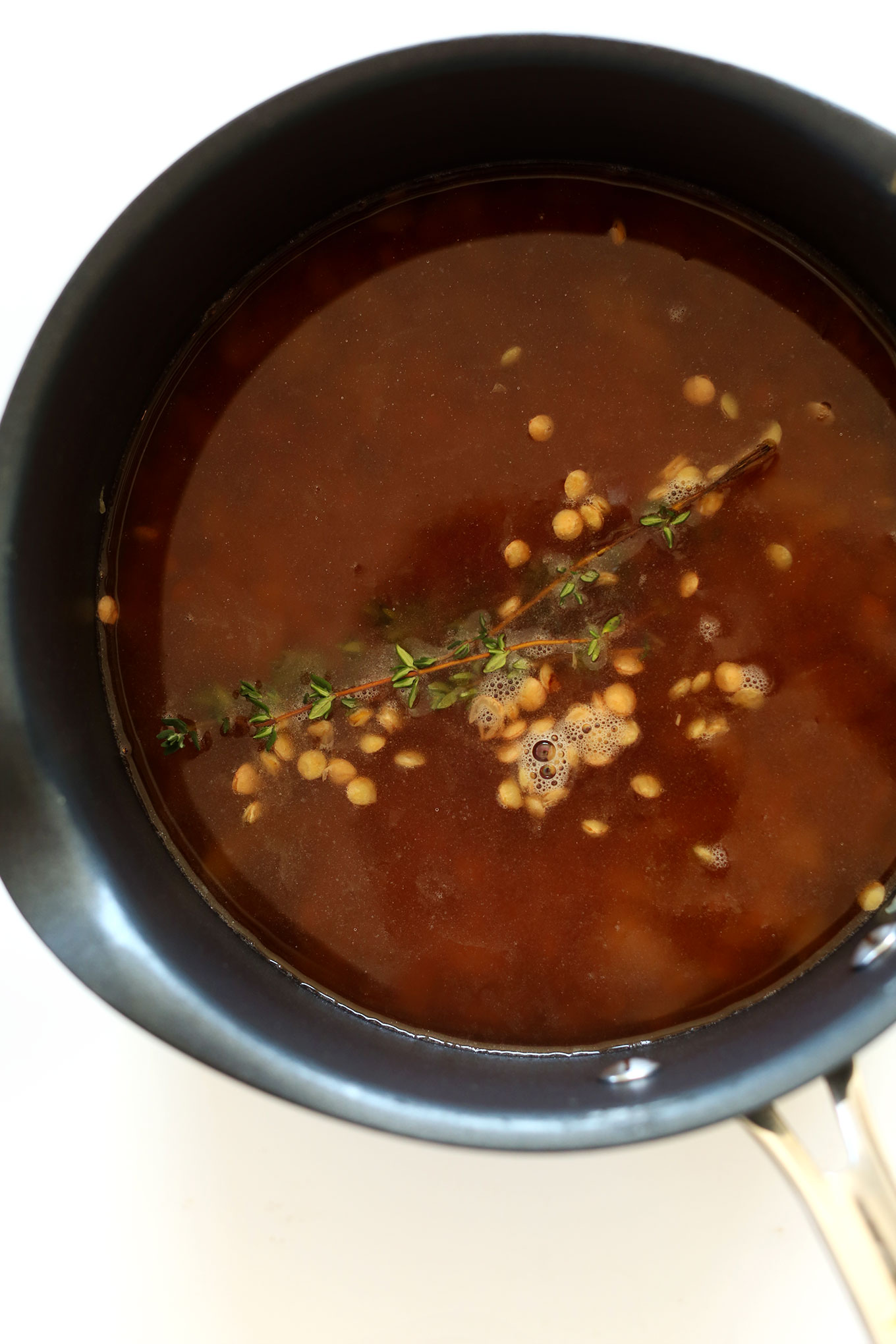 Cooking lentils in broth with fresh thyme sprigs