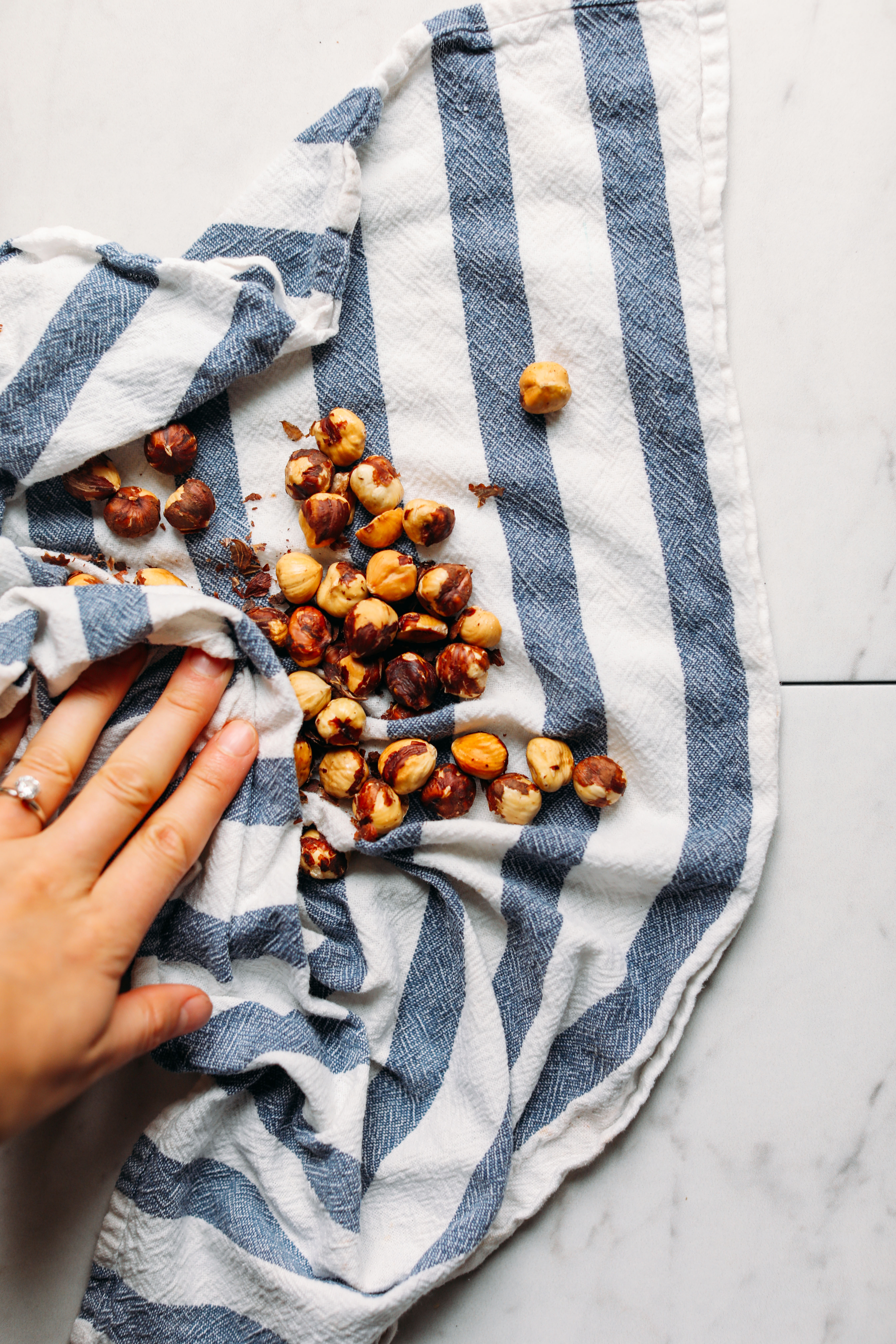 Using a dish towel to remove the skins of roasted hazelnuts