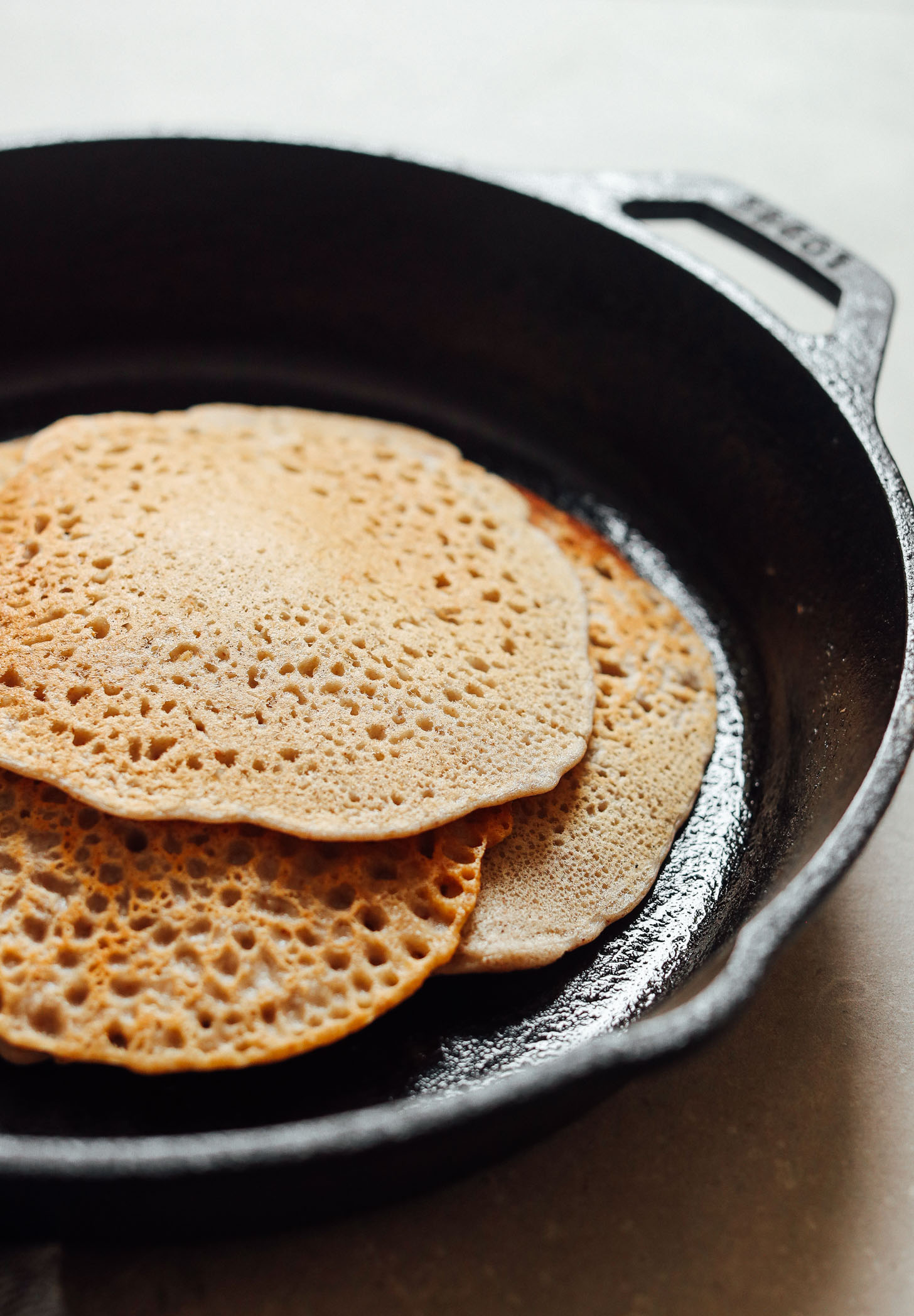 A stack of vegan gluten-free crepes in a cast iron skillet