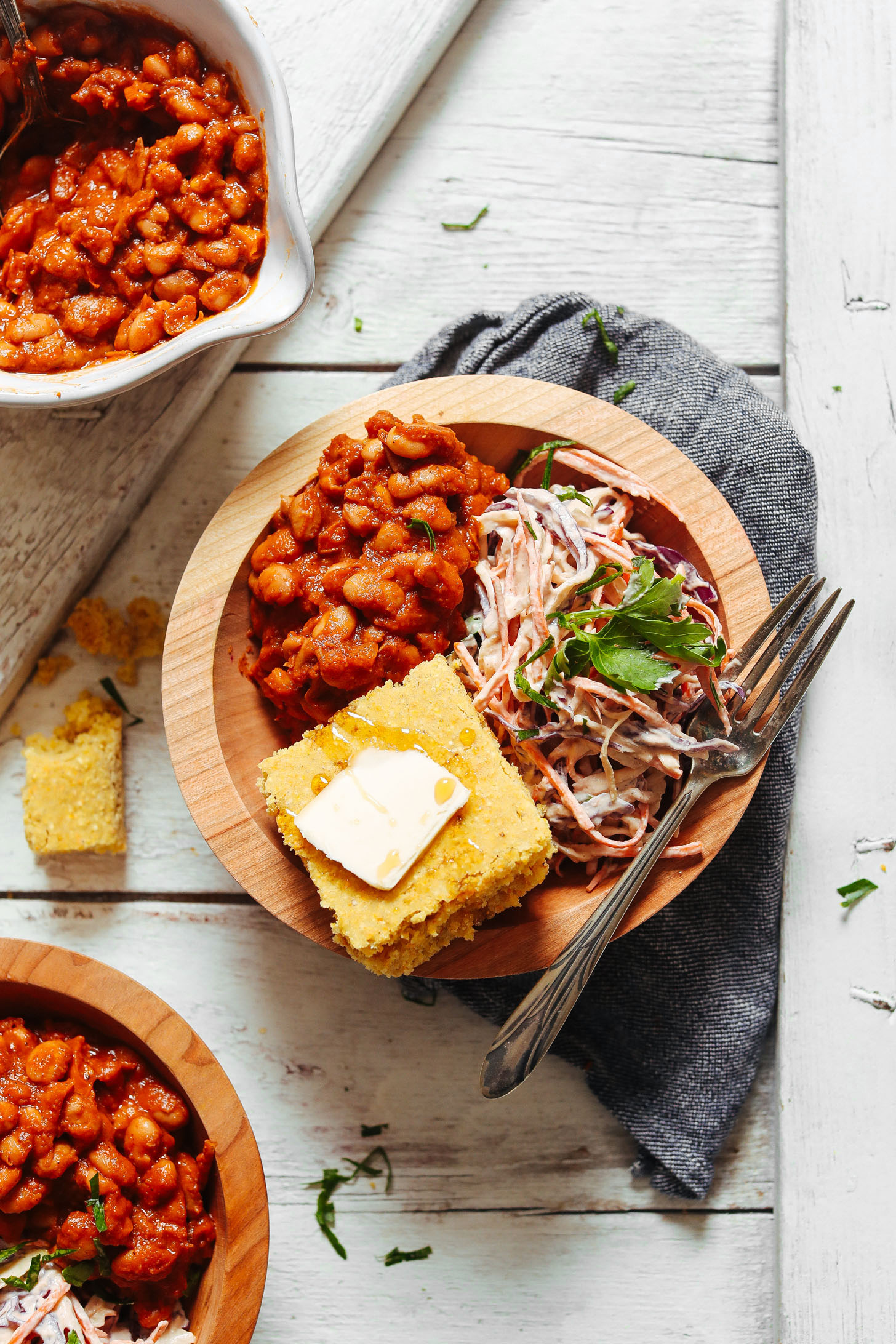 Close up shot of a bowl of Baked Beans, Vegan Coleslaw, and GF Cornbread with Vegan Butter