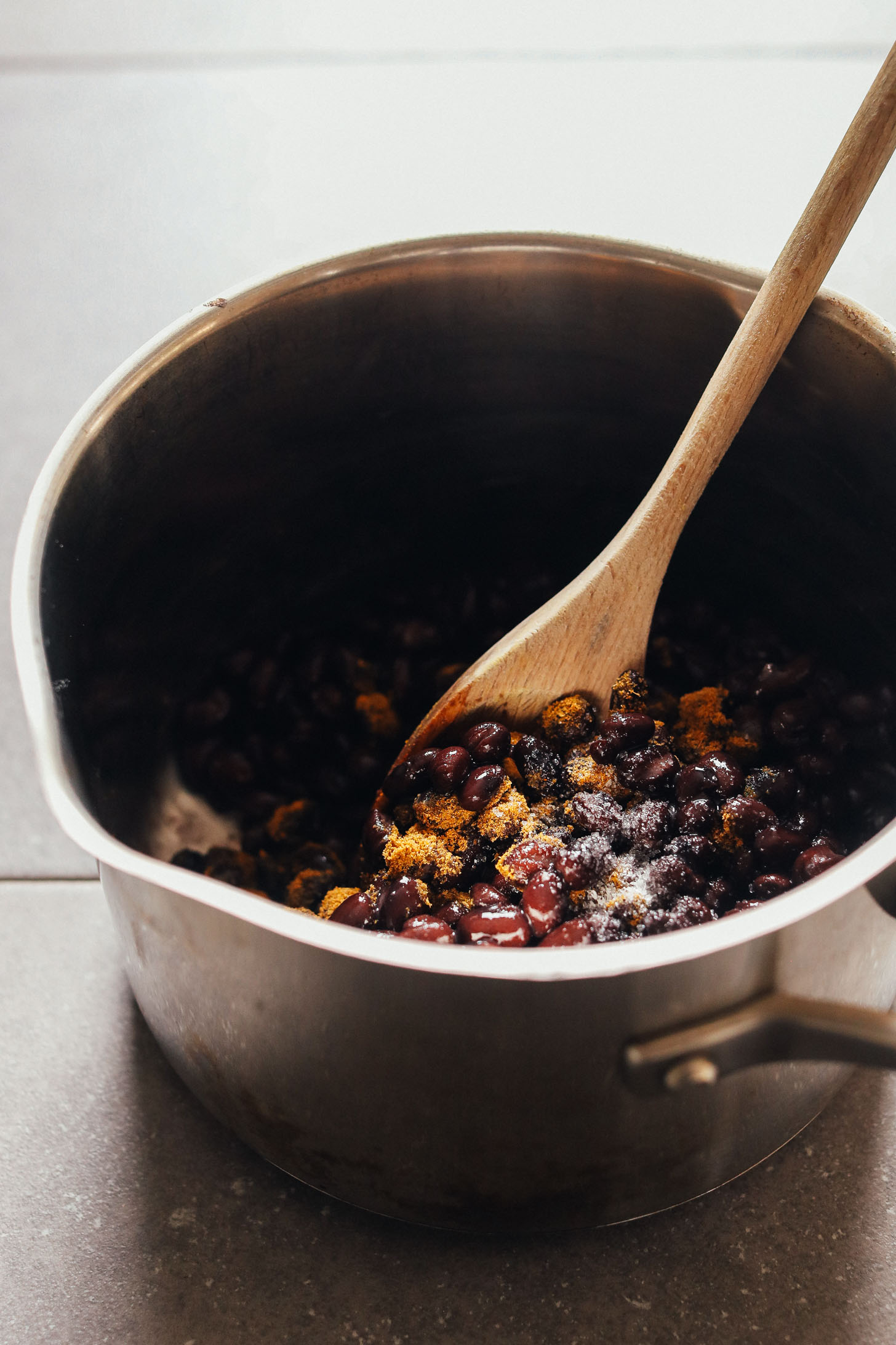 Stirring black beans and spices in a saucepan for homemade vegan enchiladas