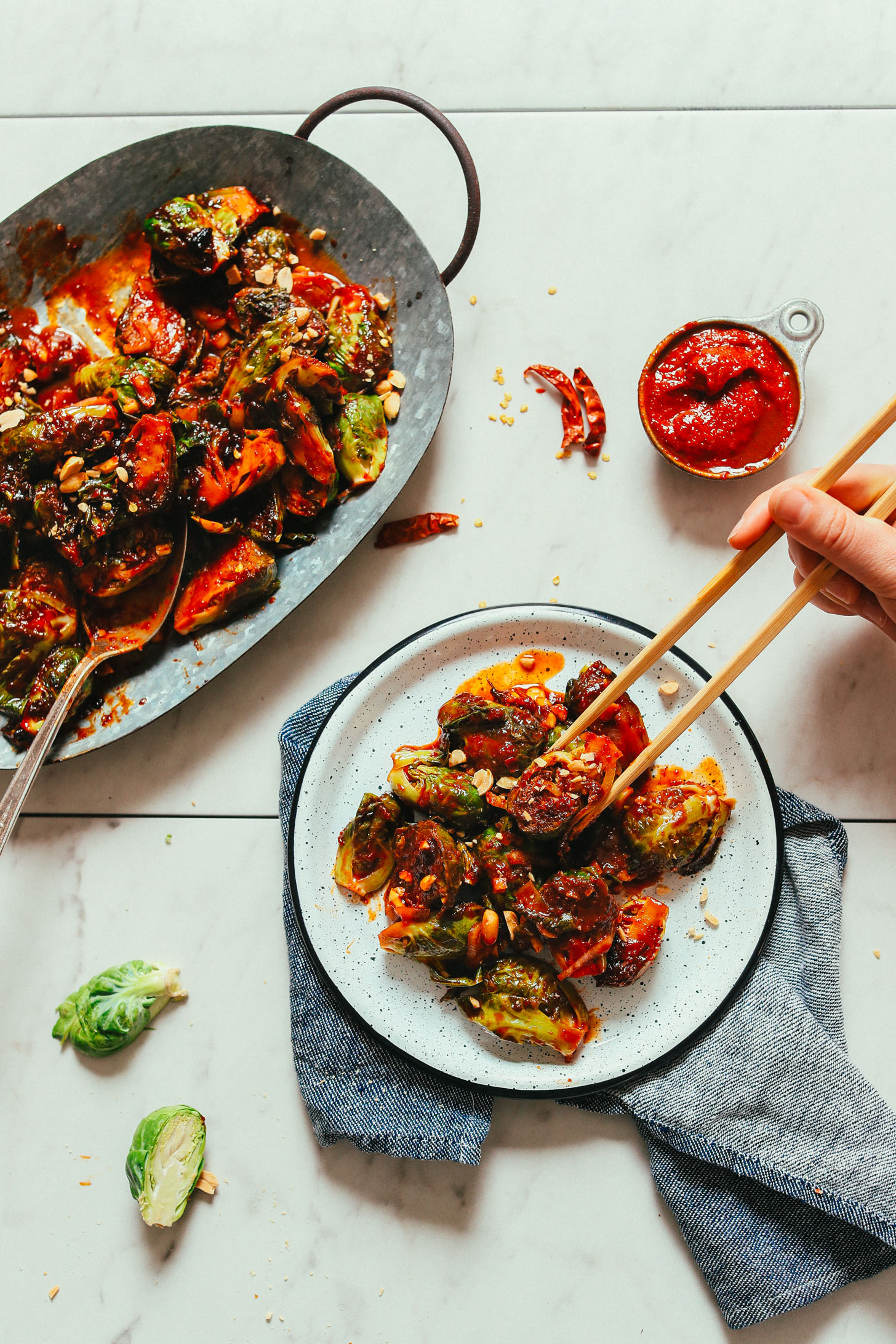 A plate and platter of our vegan Gochujang Stir-Fried Brussels Sprouts