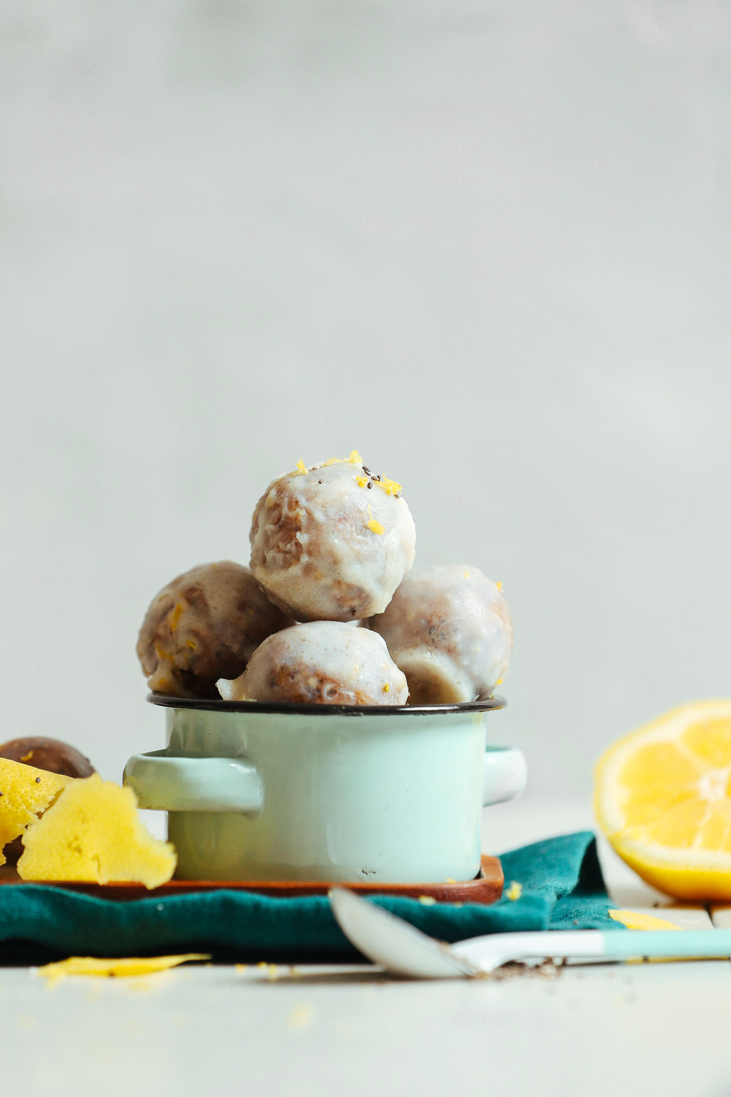 A small blue bowl with no bake vegan donut holes that are scented with lemon zest, lemon juice, and poppy seeds.