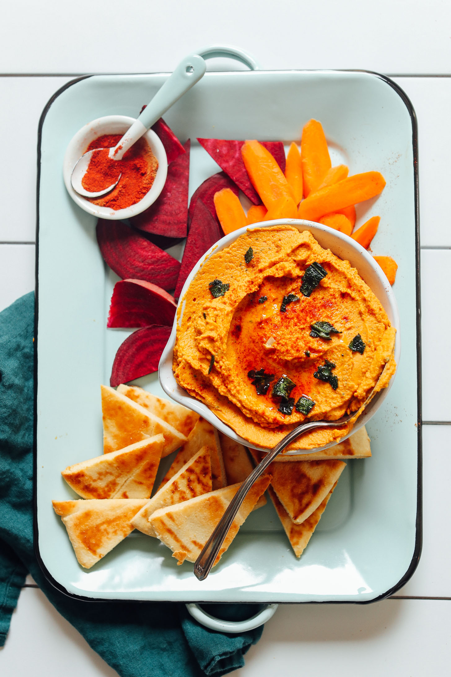 Tray with a bowl of our White Bean Pumpkin Hummus recipe with beet, carrot, and pita for dipping