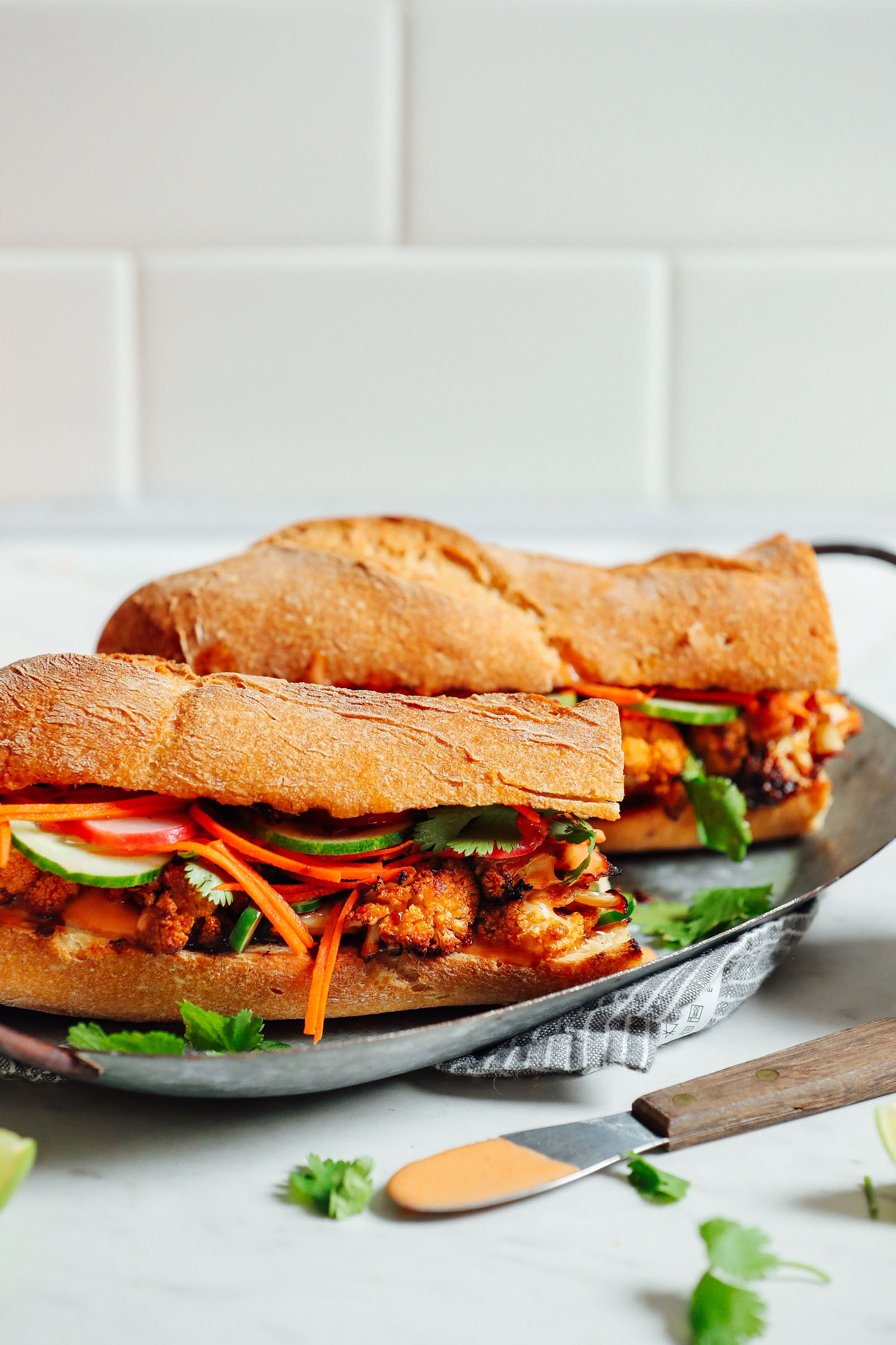 Close up shot of two Cauliflower Banh Mi sandwiches on a metal tray