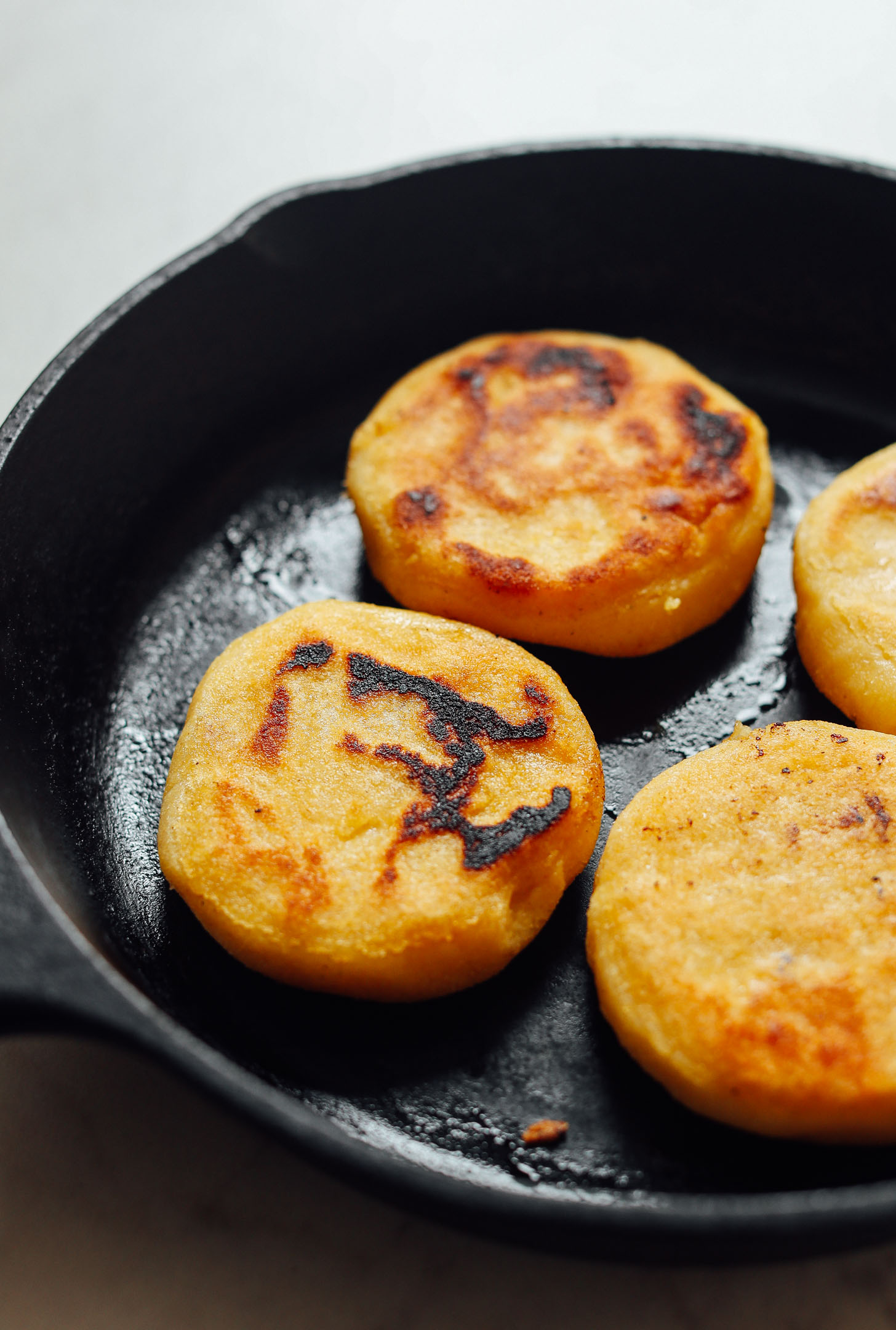 Cooking homemade gluten-free Arepas in a cast-iron skillet
