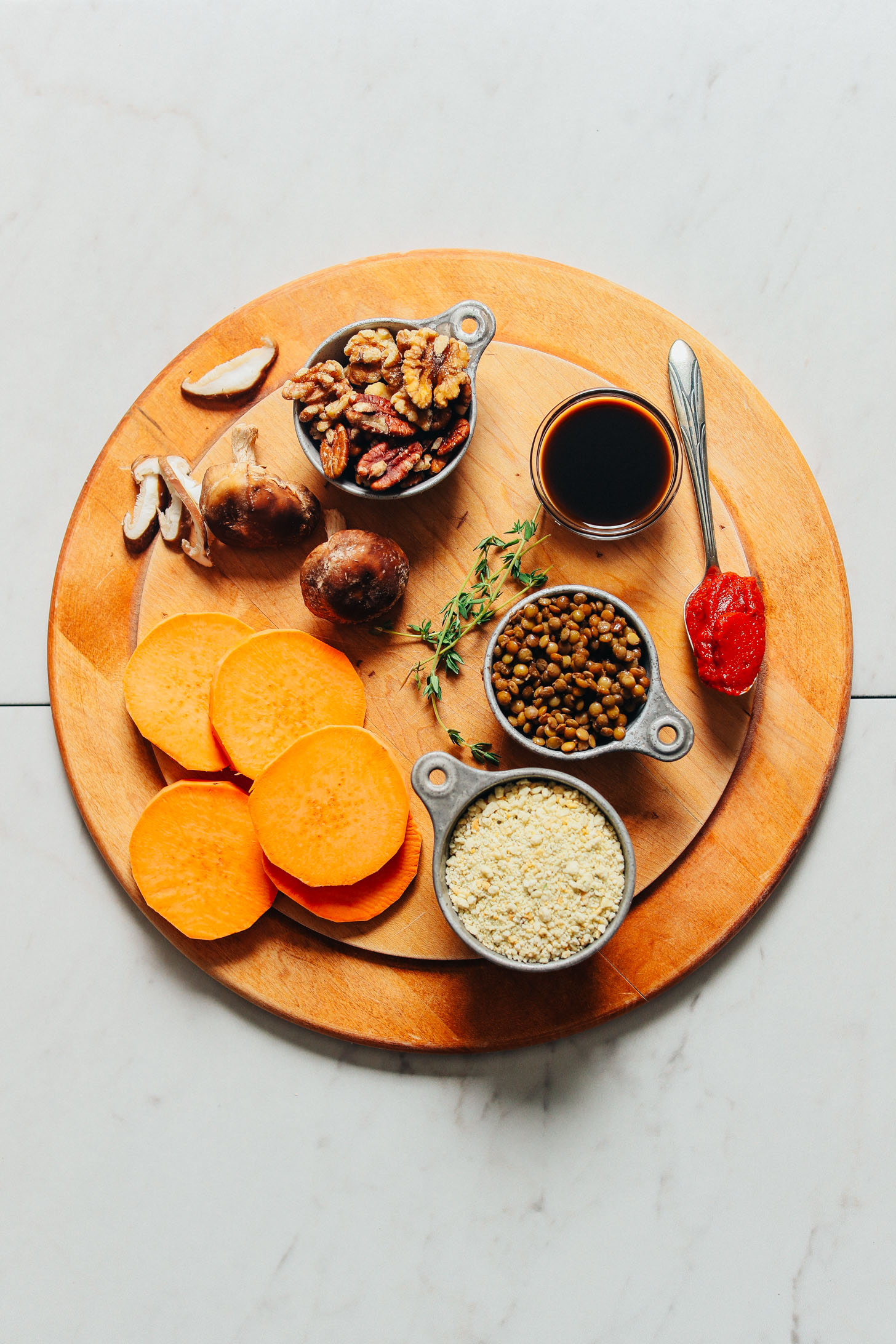 Wood cutting board filled with lentils, sweet potatoes, and other ingredients for making vegan meatloaf