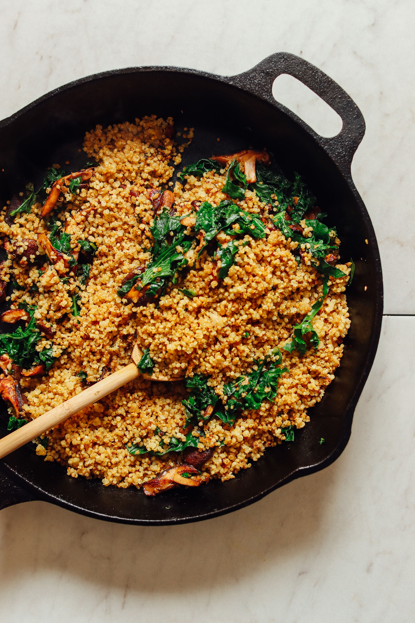 Cooking quinoa, mushrooms, and kale in a cast-iron skillet for our vegan stuffed butternut squash recipe