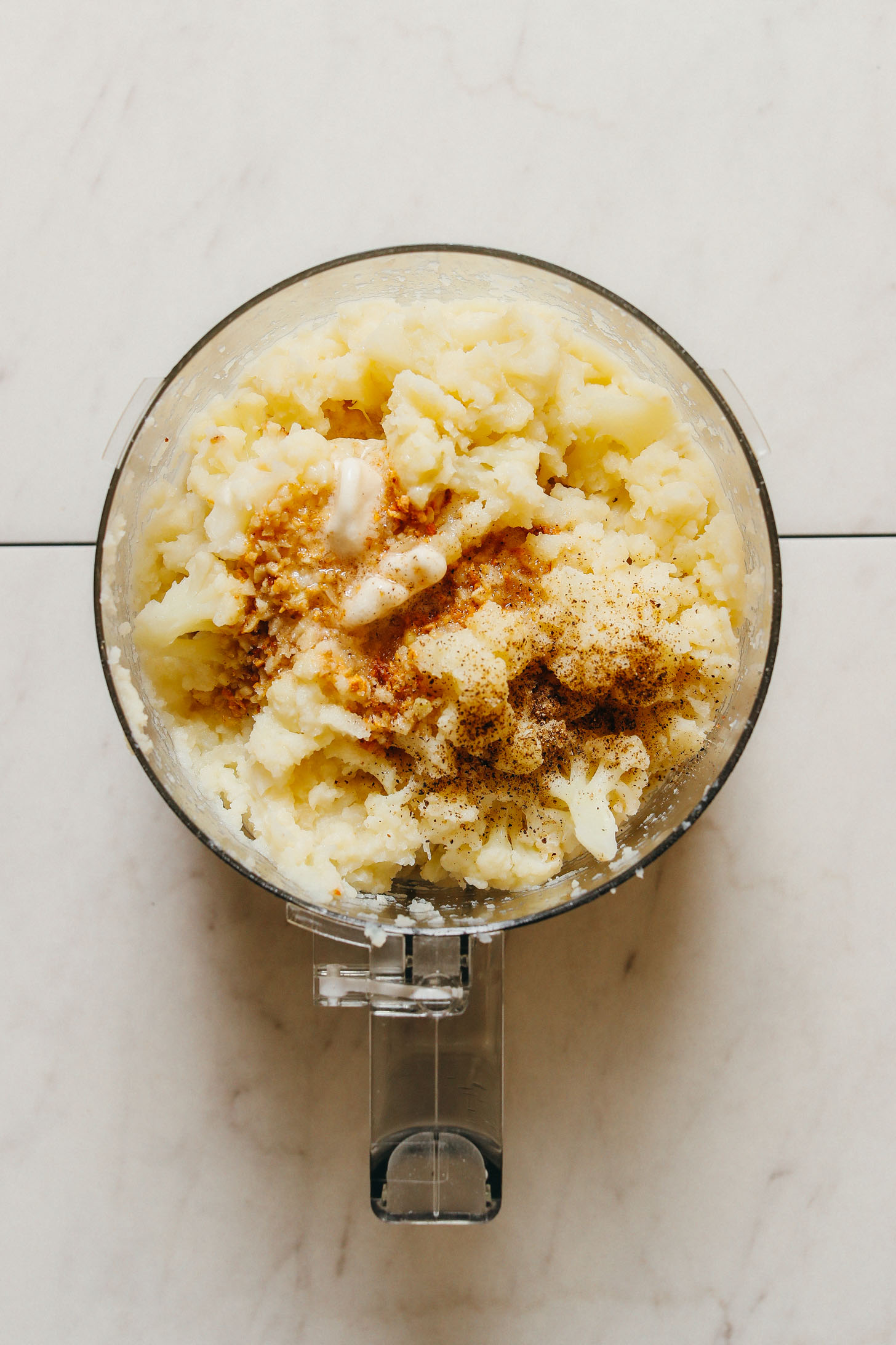 Food processor with mashed cauliflower, spices, and vegan butter for a delicious vegan Thanksgiving side recipe