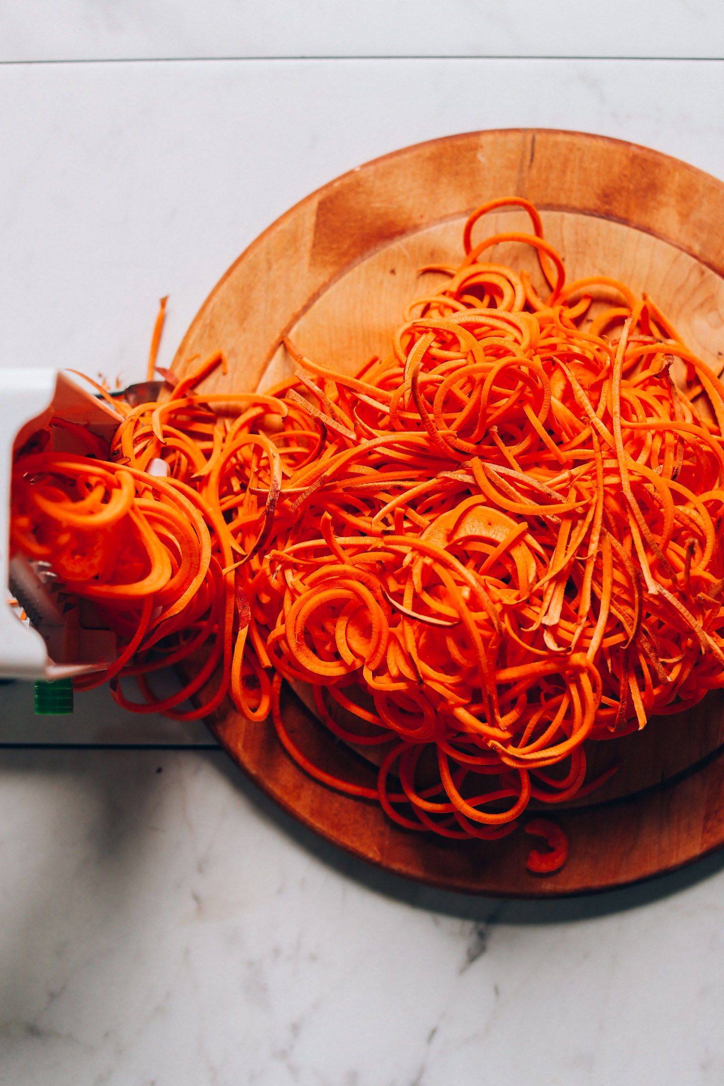 Cutting board with spiralized sweet potatoes for making Sweet Potato Hashbrowns