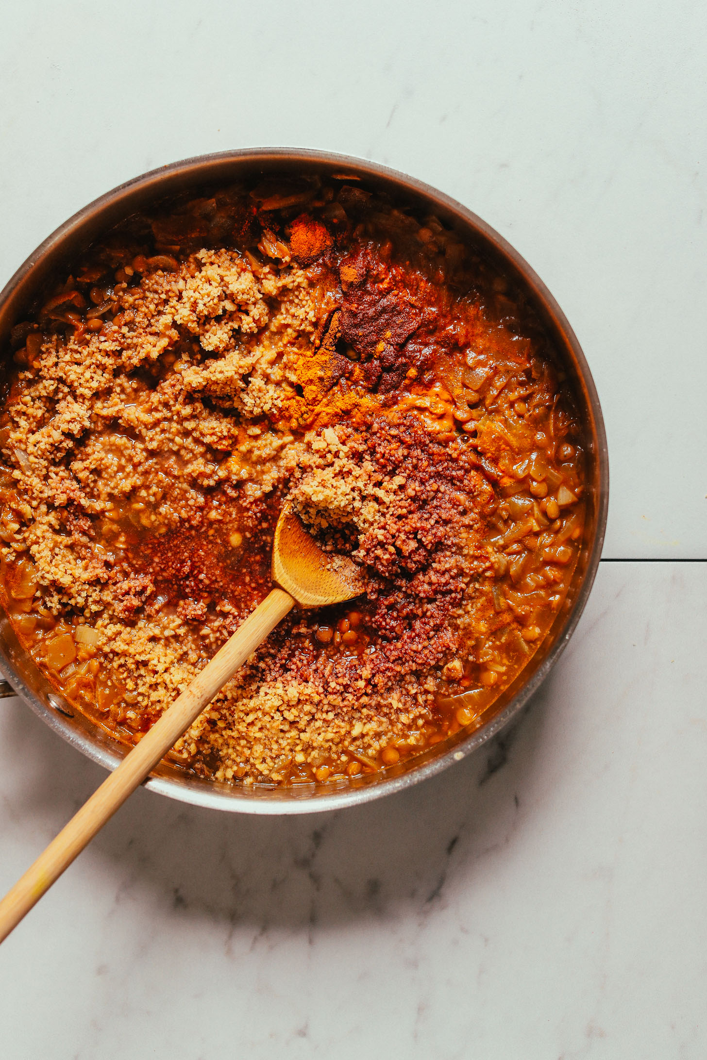 Stirring a skillet of our satisfying vegan Lentil Fesenjan recipe