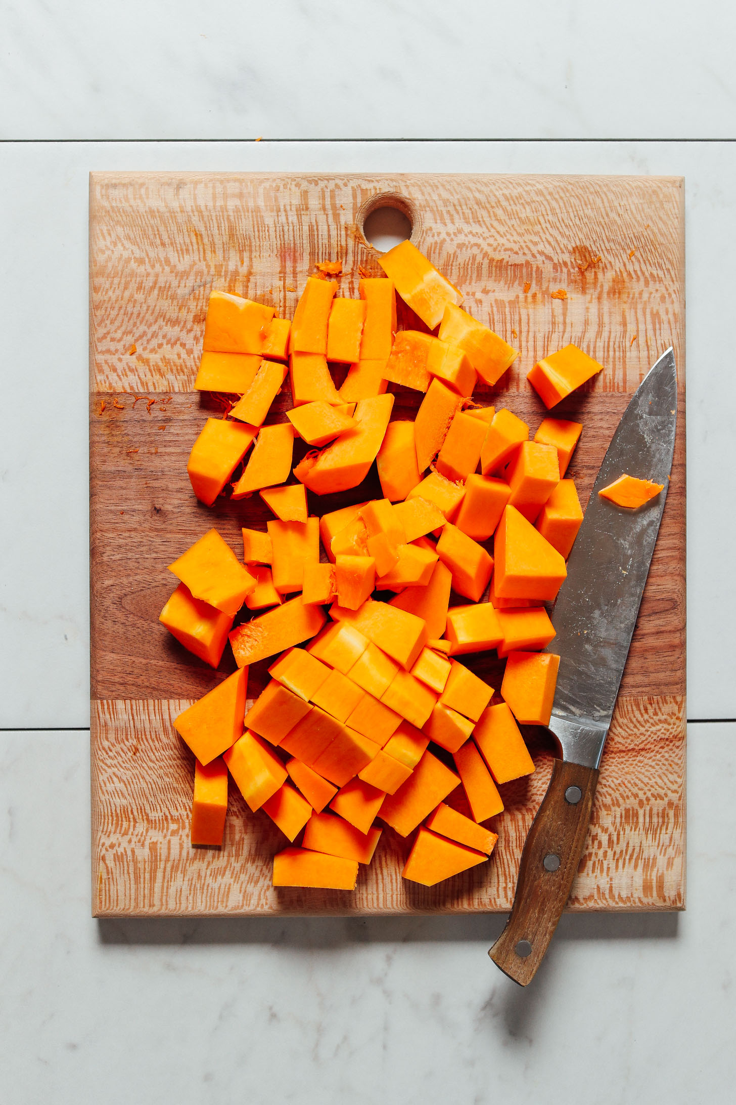 Cutting board filled with cubed butternut squash for our How to Cut Butternut Squash Tutorial