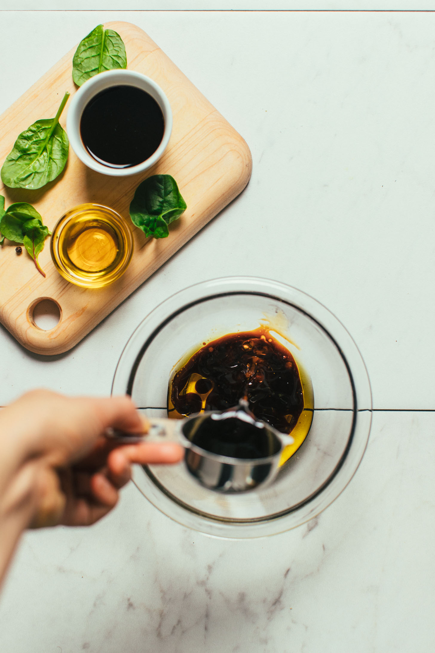 Pouring balsamic vinegar into a bowl for simple homemade dressing