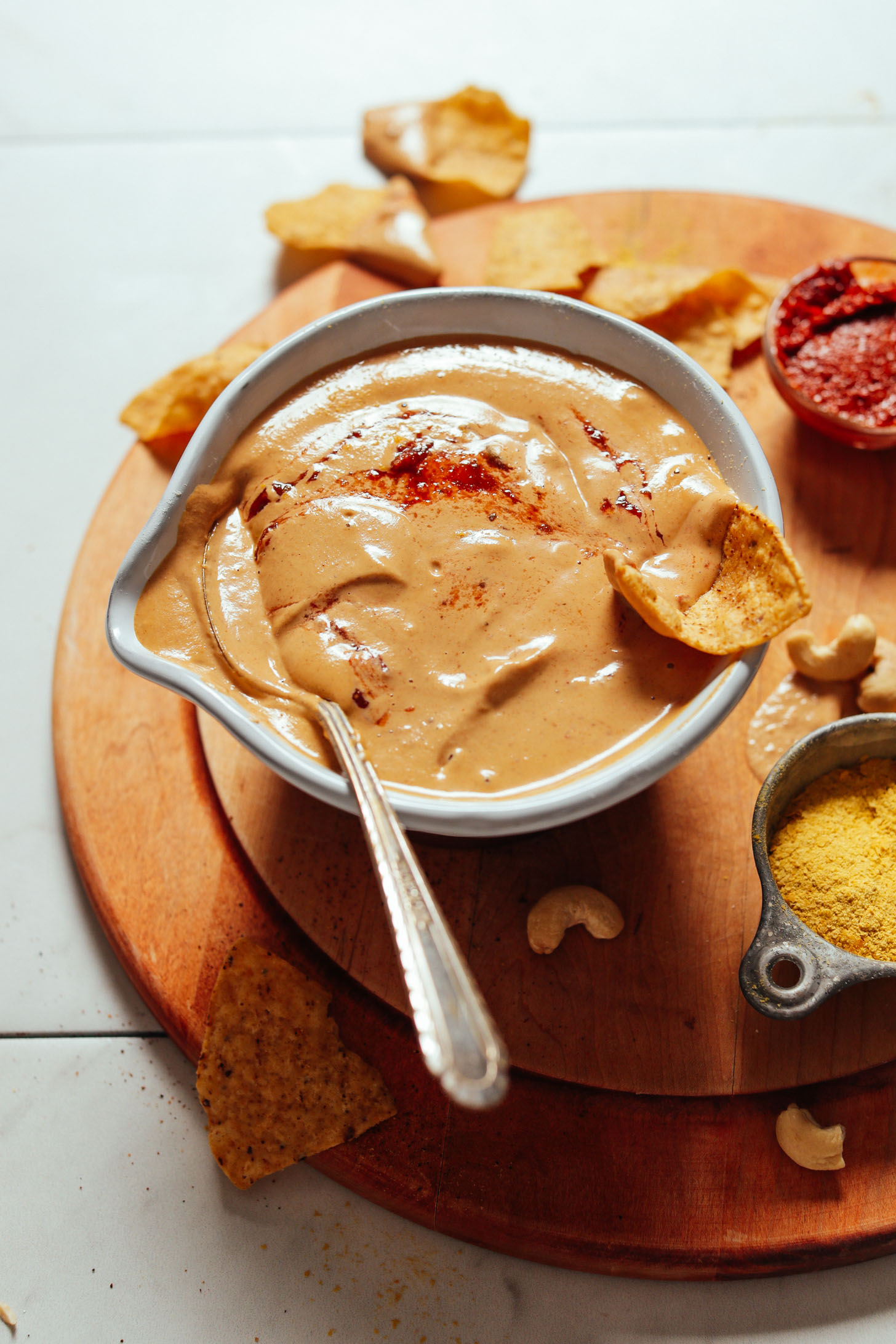 Image of vegan cashew queso in a bowl with a spoon on the left side and chip on the right side
