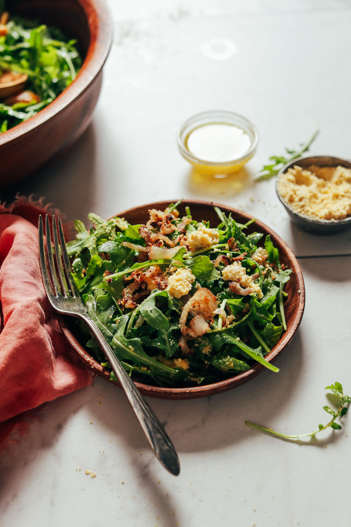 Wooden salad plate with a serving of our Lemony Arugula Salad with Crispy Shallot recipe