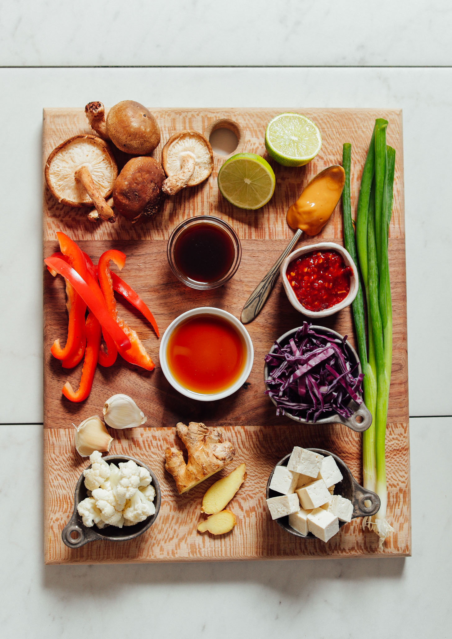 Wood cutting board with ingredients for making our 20-Minute Tofu Stir Fry recipe