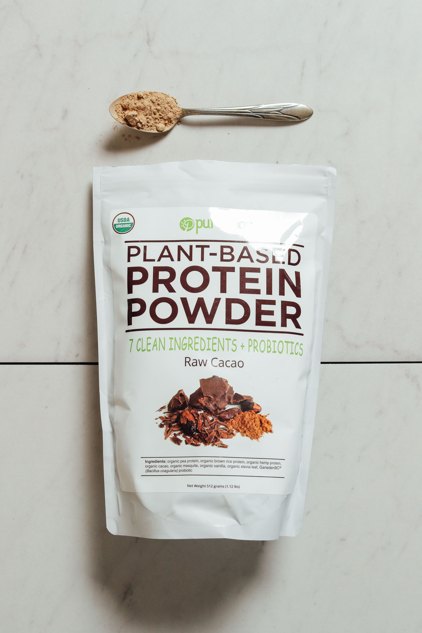 Bag and spoonful of Pure Food Chocolate Protein Powder
