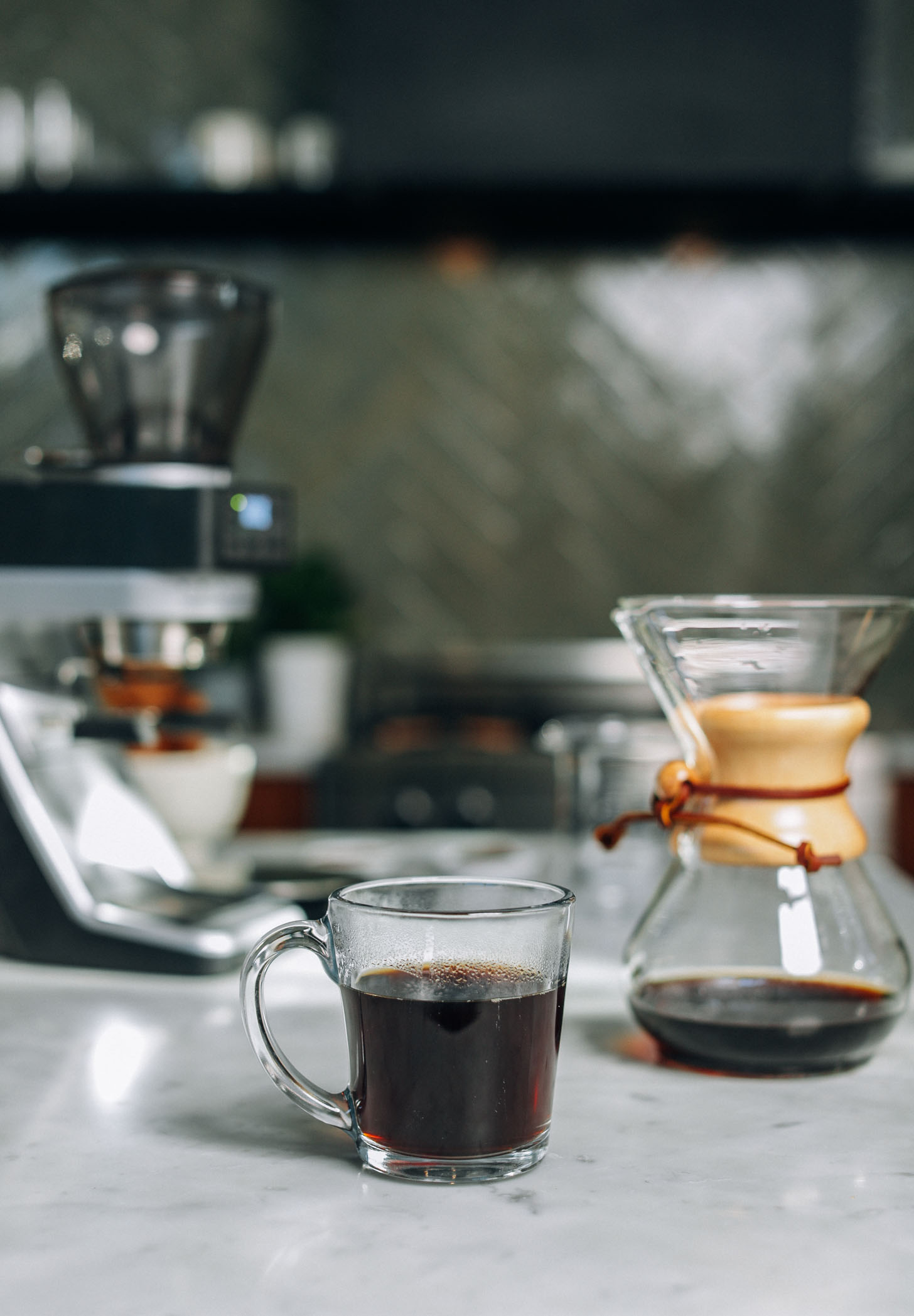 Coffee grinder, mug of coffee, and drip coffee maker