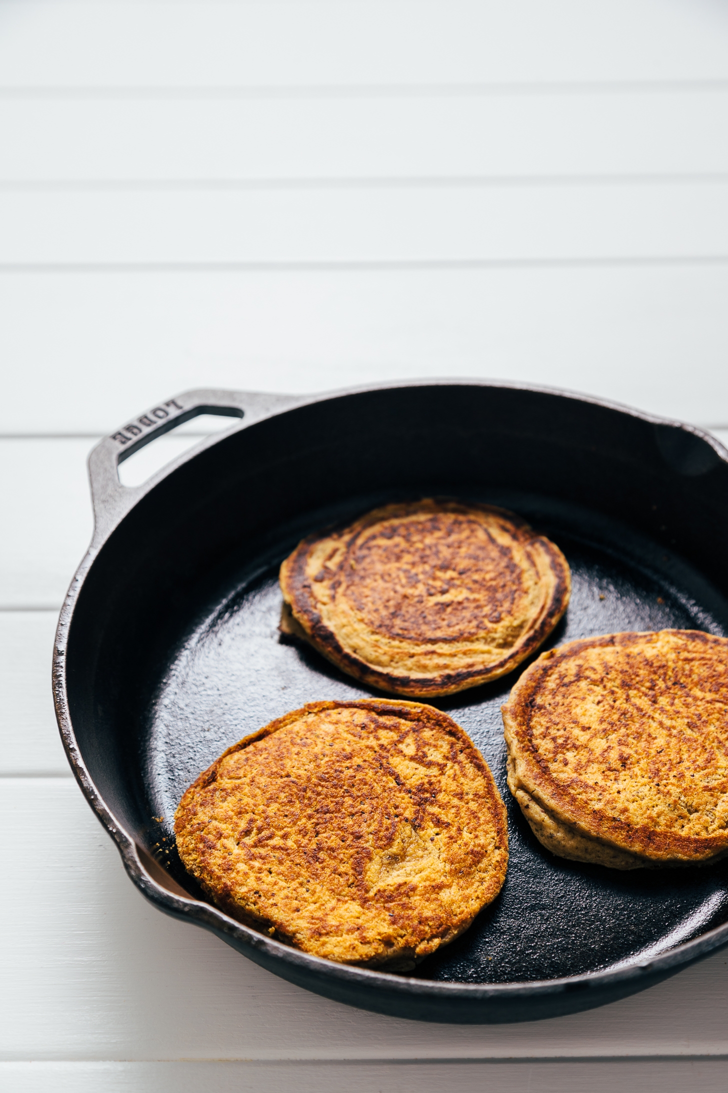 Cooking vegan Peanut Butter Protein Pancakes in a cast-iron skillet