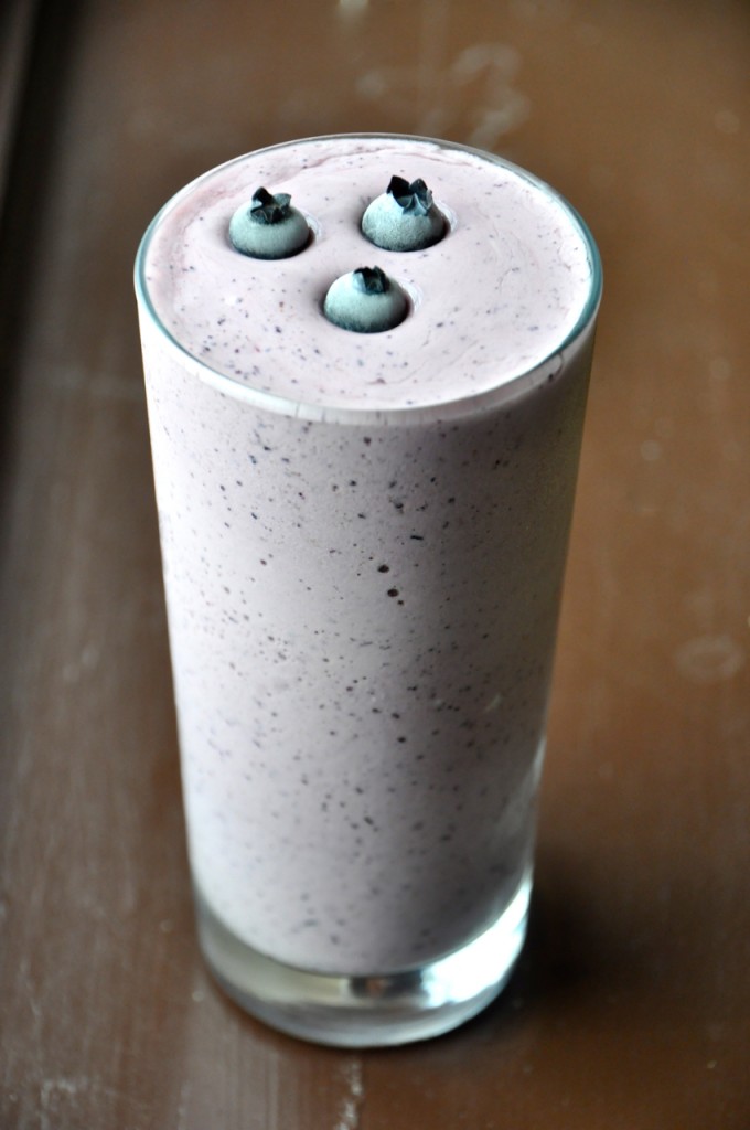Tall glass of our Blueberry Maple Protein Shake recipe topped with fresh blueberries