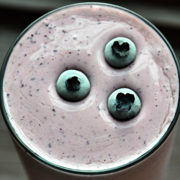 Shot of the top of a glass of our Blueberry Maple Protein Shake topped with fresh blueberries