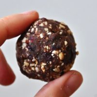 Close up shot of a Chocolate Cashew Cookie Larabar Bite held between two fingers
