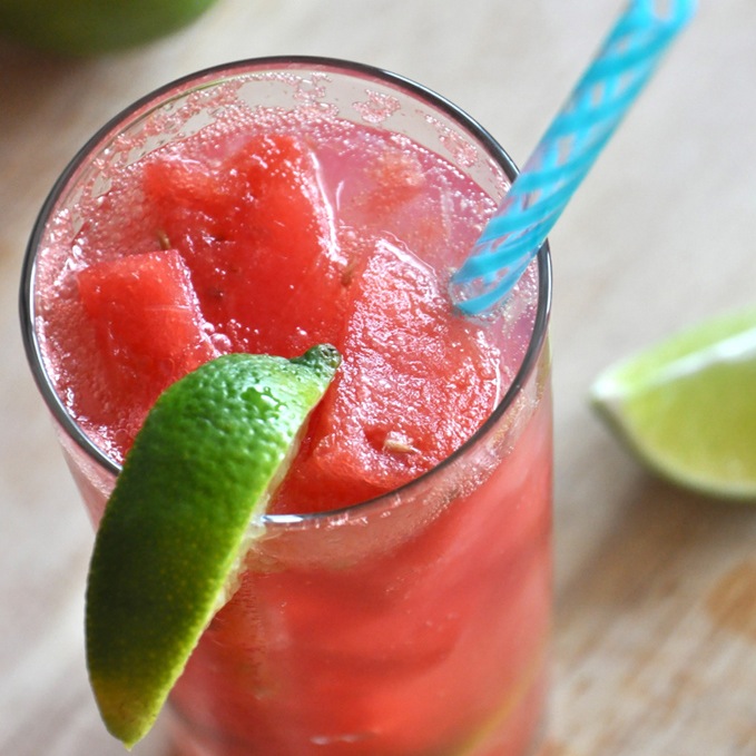 Tall glass of our Watermelon Limeade Cocktail recipe with a lime wedge on the rim
