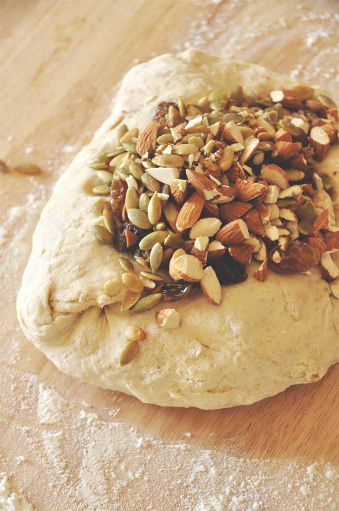 Loaf of unbaked Muesli Bread with almonds, pumpkin seeds, and raisins on top