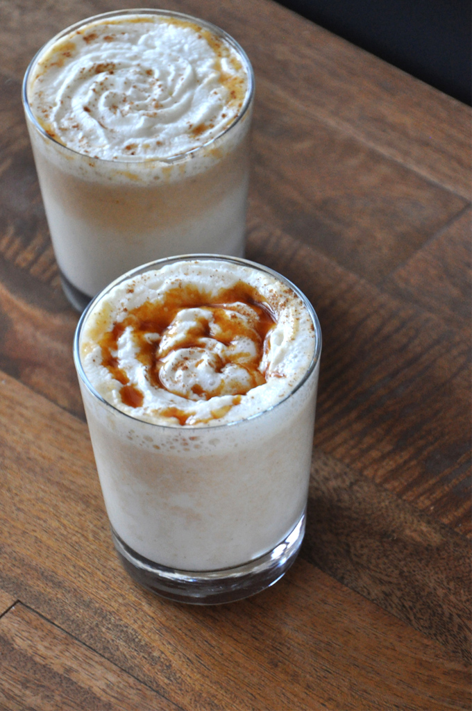 Glasses of Boozy Pumpkin White Hot Chocolate with one topped with caramel sauce