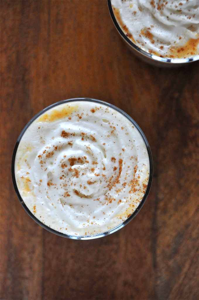 Top down shot of a whipped cream spiral topped with cinnamon on top of a Boozy Pumpkin White Hot Chocolate