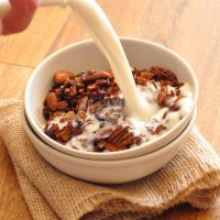 Pouring dairy-free milk into a bowl of Nut-and-Honey Coconut Granola