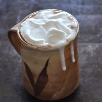 Overflowing mug of Mexican Hot Chocolate with Coconut Whipped Cream