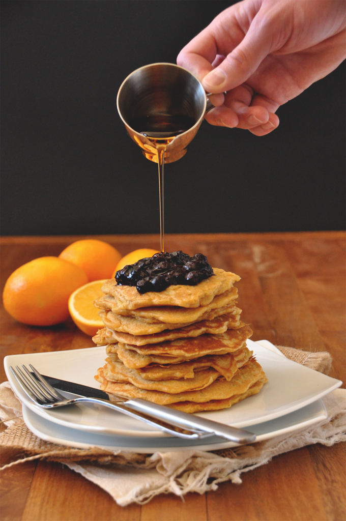Pouring syrup onto a giant stack of our Whole Wheat Griddle Cakes recipe