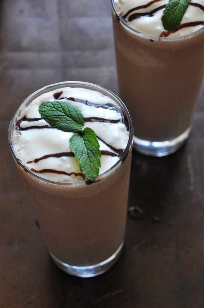 Two tall glasses of our Peppermint Mocha Frappe recipe topped with whipped cream, chocolate sauce, and fresh mint