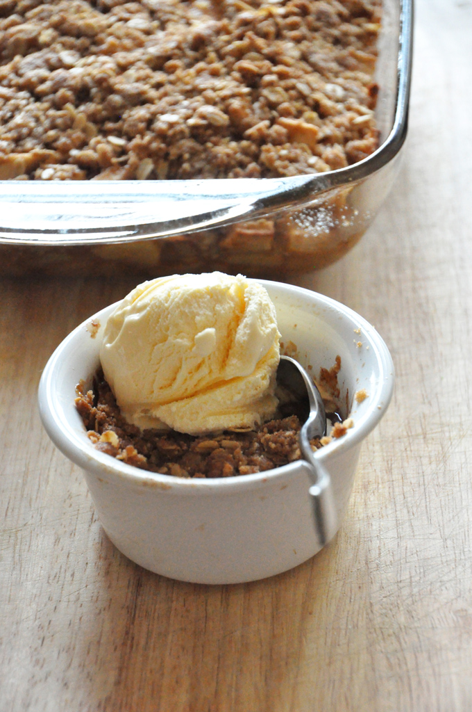 Bowl of Gluten-Free Vegan Apple Crisp with ice cream and the rest of the crisp behind it