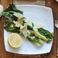 Plate of Broiled Romaine Salad with Rosemary Caesar Dressing and a lemon half