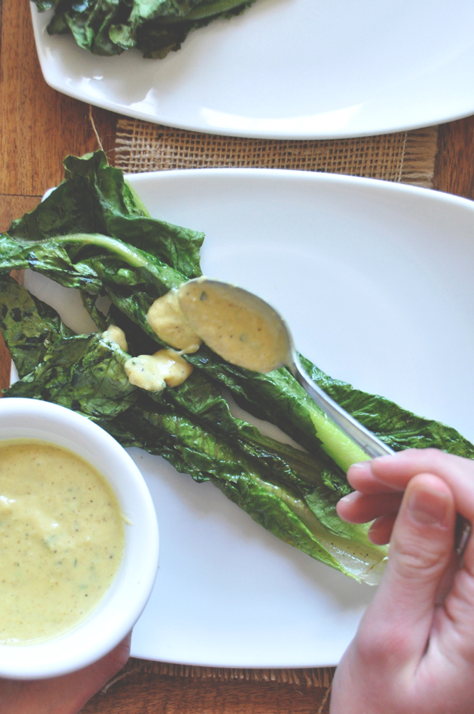 Spooning Rosemary Caesar dressing onto a leaf of Broiled Romaine
