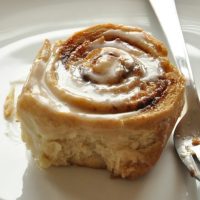 Close up shot of a homemade Honey Wheat Cinnamon Roll topped with icing