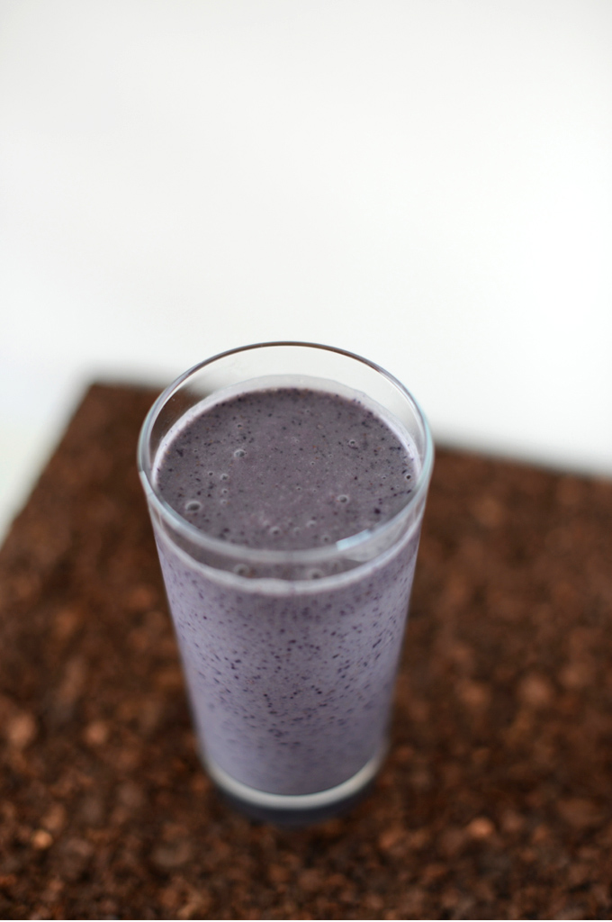 Glass of our PB and Jelly Smoothie recipe on a cutting board