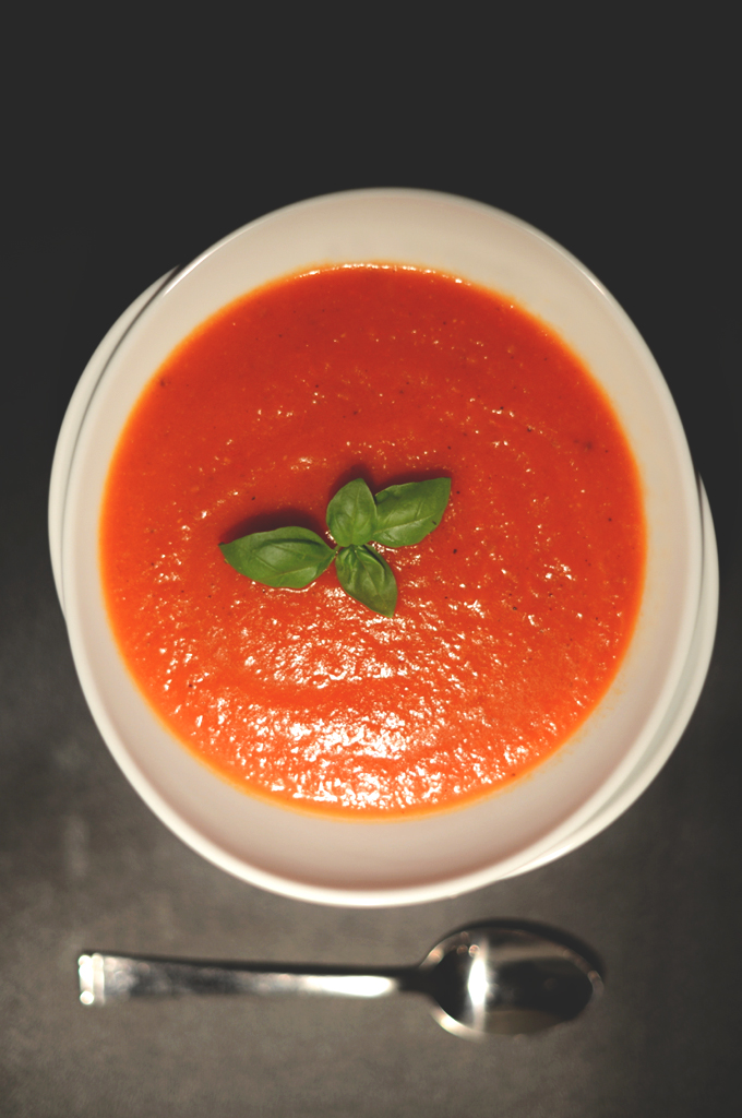 Bowl of Vegan Roasted Red Pepper Tomato Soup topped with fresh basil