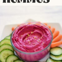 Bowl of vegan gluten-free roasted beet hummus with baby carrots and sliced cucumbers around it