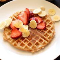 Plate with a Gluten-Free Vegan Oatmeal Waffle topped with fresh fruit and syrup