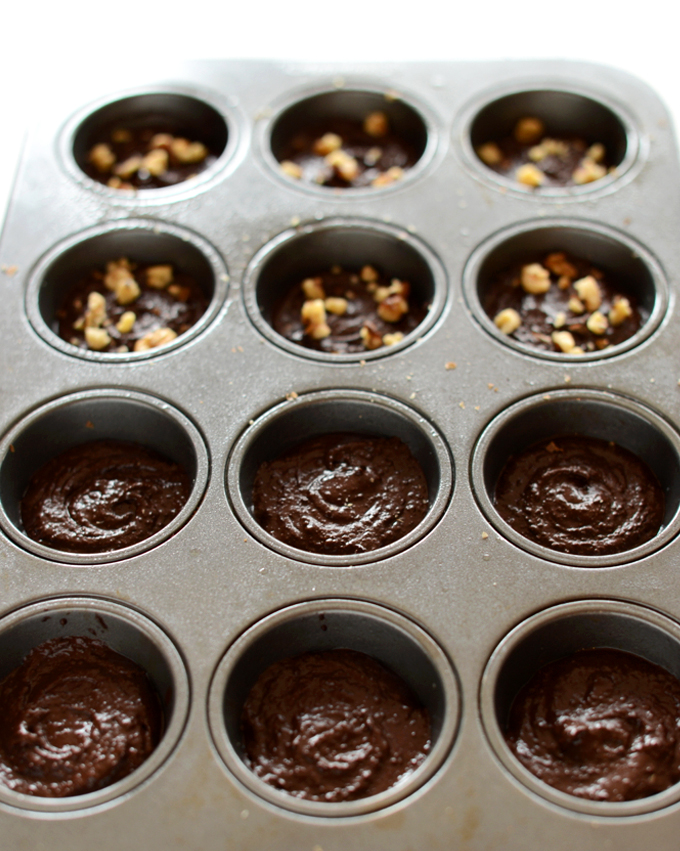 Muffin tin filled with Black Bean Brownies with half of them topped with walnuts