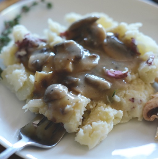 Using a fork to pick up a bite of Cauliflower Mashed Potatoes topped with Mushroom Gravy