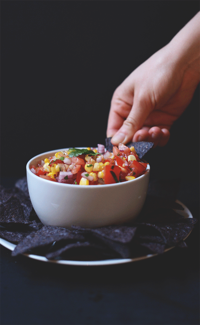 Using a tortilla chip to grab a scoop of Simple Grilled Corn Salsa