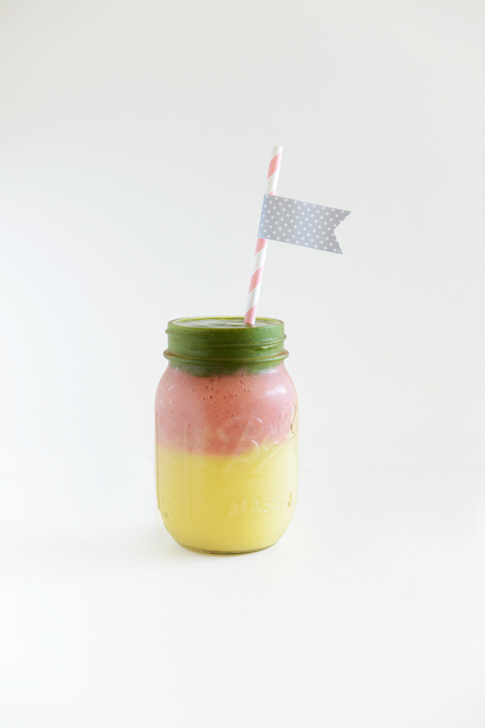 Jar of our Layered Mango Stoplight Smoothie recipe with a flag straw in it