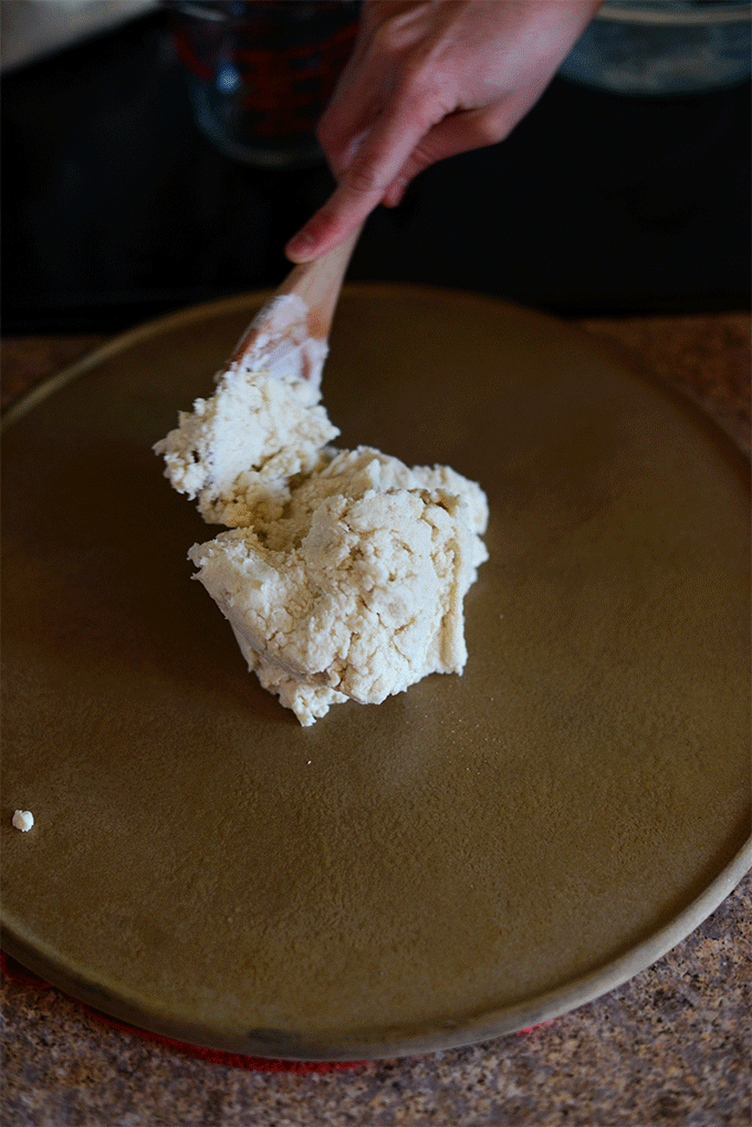 Spreading Gluten-Free Pizza Crust dough onto a pizza stone
